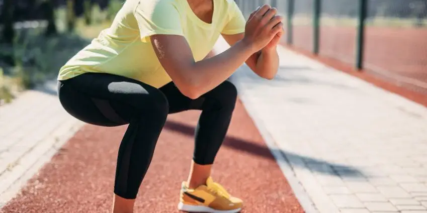 avoiding-low-back- injuries-close-up-sportswoman-doing-squats-exercises-court